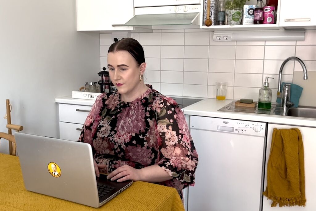 Noora Korpela istuu tietokoneen äärellä keittiössä