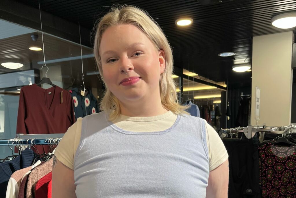 Second hand -myyjänä työskentelevä Saimi Alatalo hymyilee kirpputorilla.