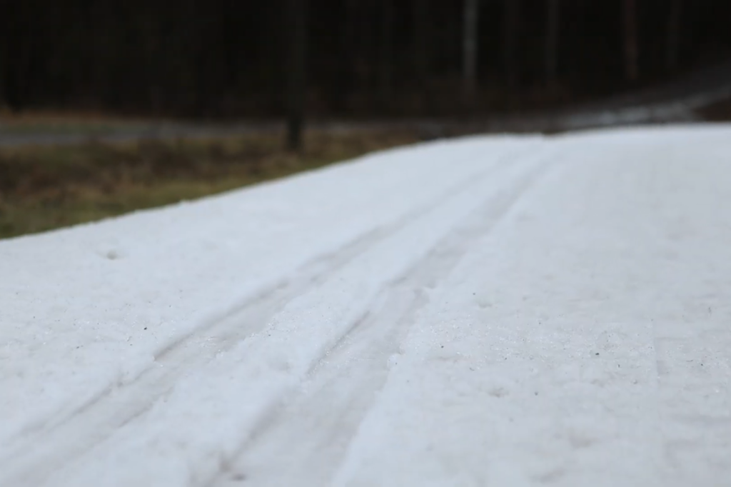 Lähikuva tykkilumiladusta ja taustalla sula maa.