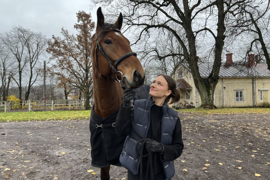 Emma Kallioniemi seisoo Samu -hevosen kanssa pihalla.