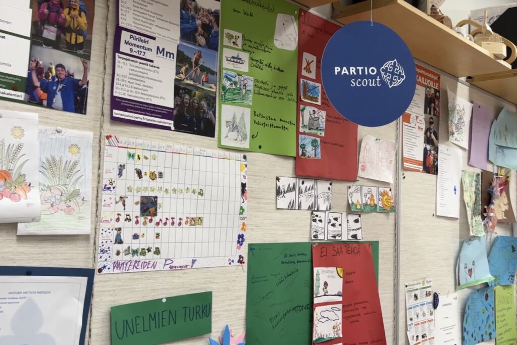 Kuvassa ilmoitustaulu, jossa partio-aiheisia julisteita ja askarteluita.