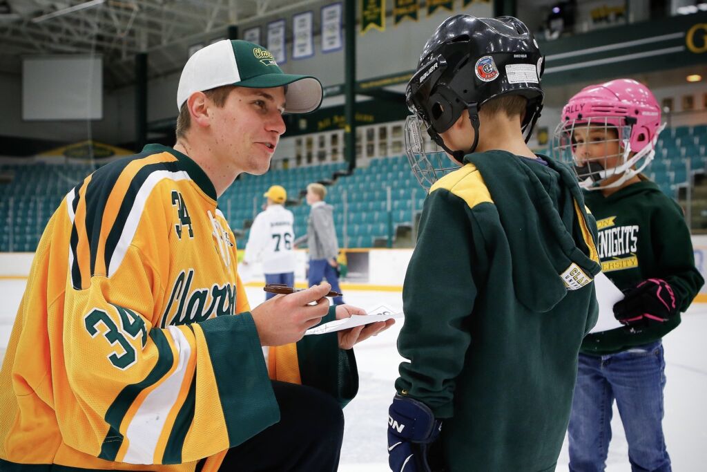 Jääkiekkoilija jäällä kahden lapsen kanssa.